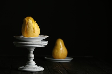 Photo of Pouring sweet syrup onto fresh ripe pear on table against dark background. Space for text