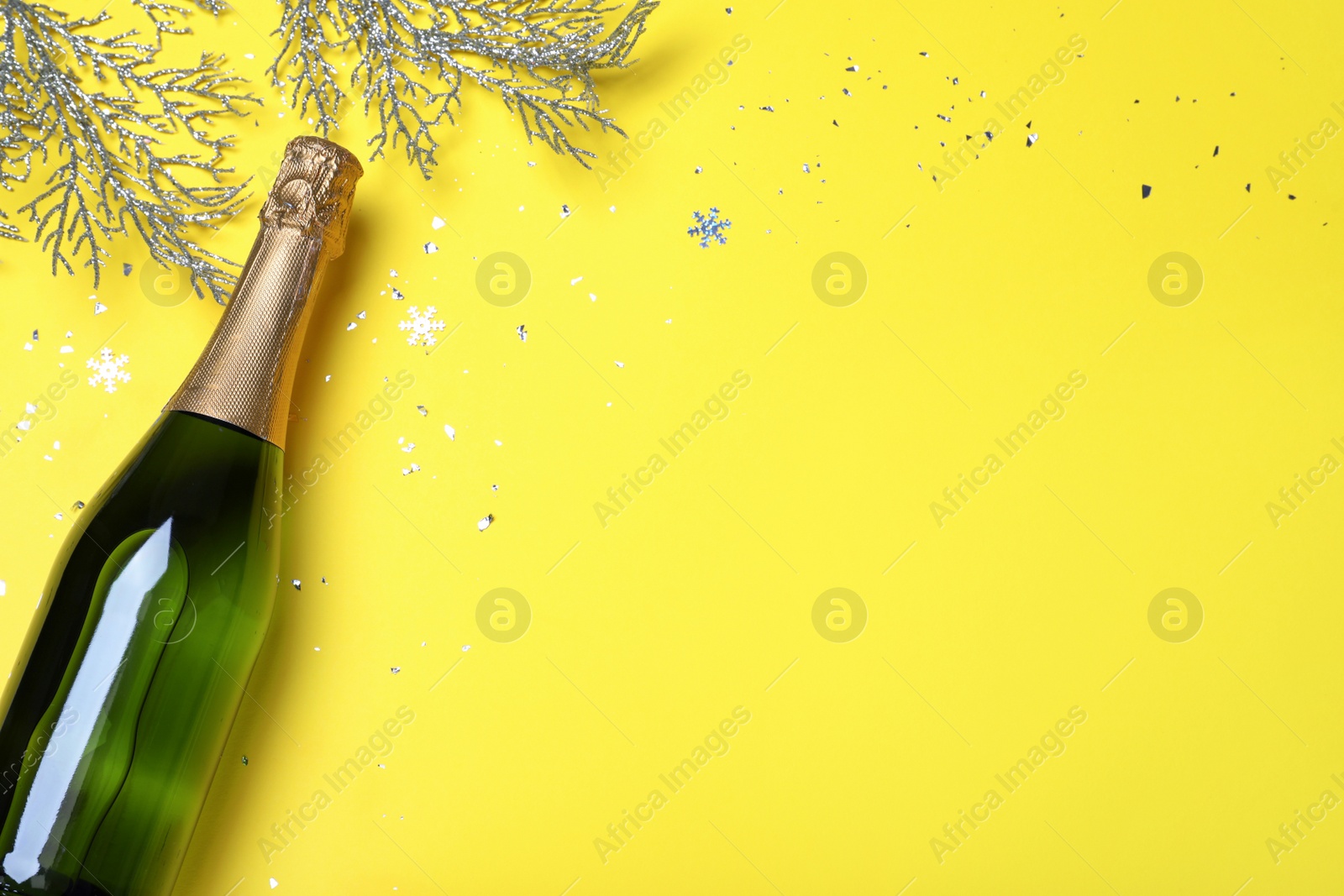 Photo of Happy New Year! Flat lay composition with bottle of sparkling wine on yellow background, space or text