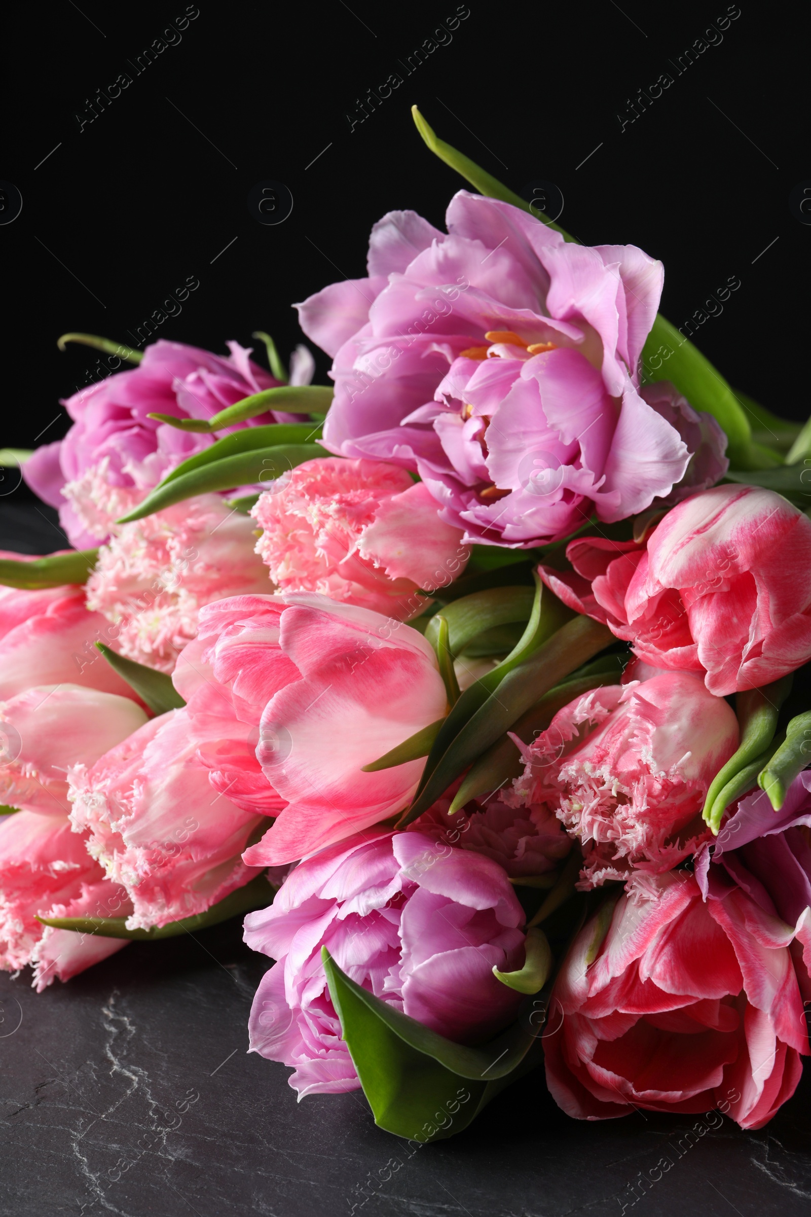 Photo of Beautiful bouquet of colorful tulip flowers on black table