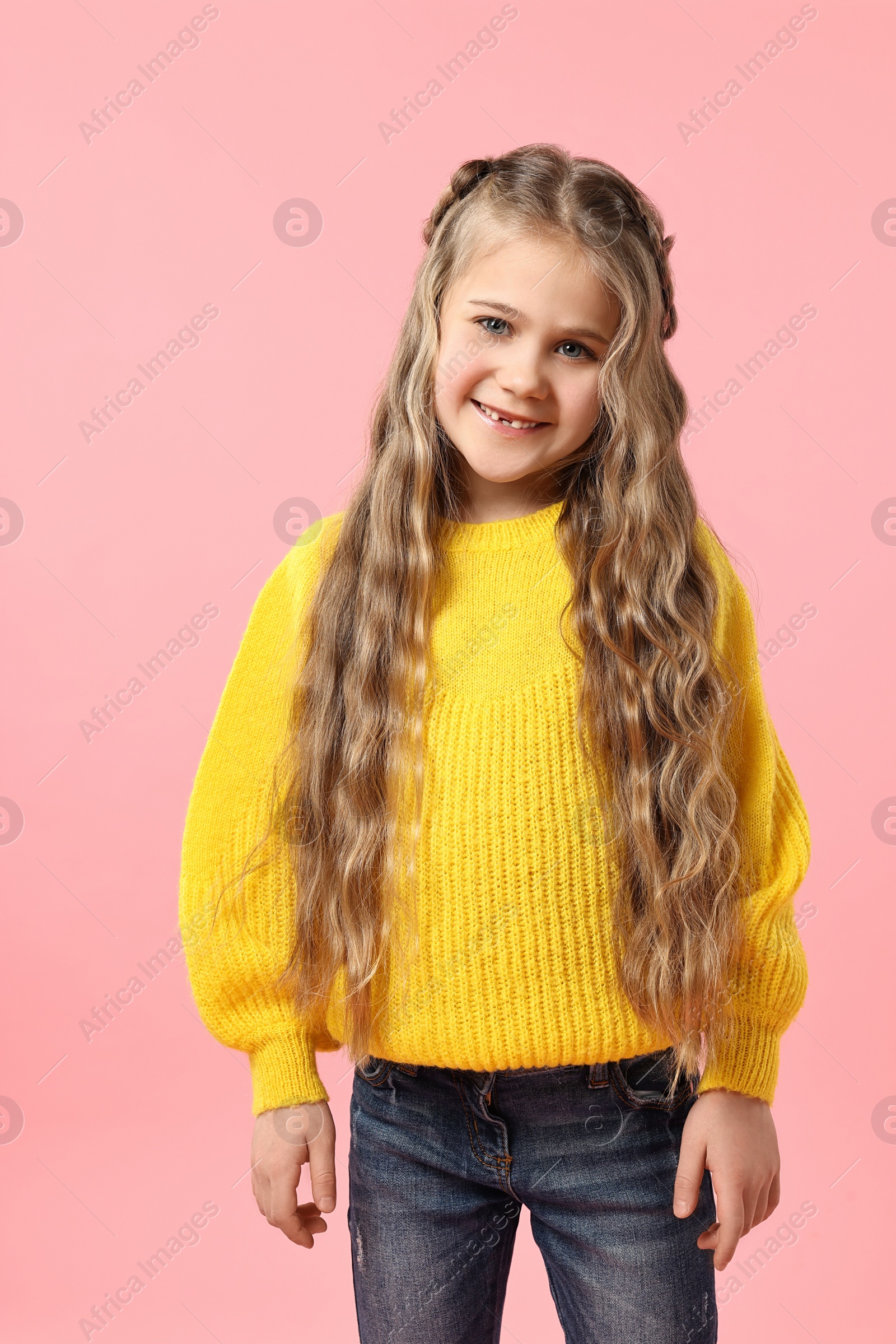 Photo of Cute little girl with braided hair on pink background