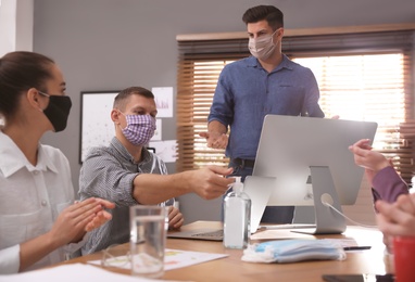 Photo of Group of coworkers with protective masks in office. Business meeting during COVID-19 pandemic