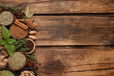 Flat lay composition with different natural spices and herbs on wooden table, space for text