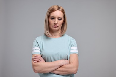 Photo of Portrait of sad woman with crossed arms on grey background