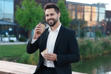 Photo of Smiling young businessman having his lunch outdoors