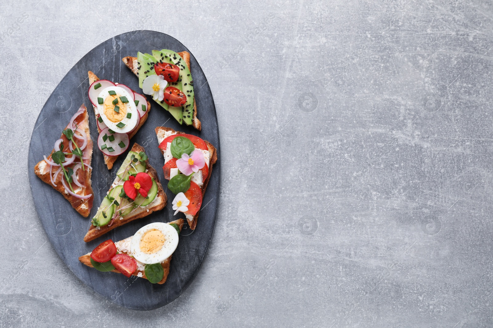 Photo of Different tasty sandwiches served on grey table, top view. Space for text