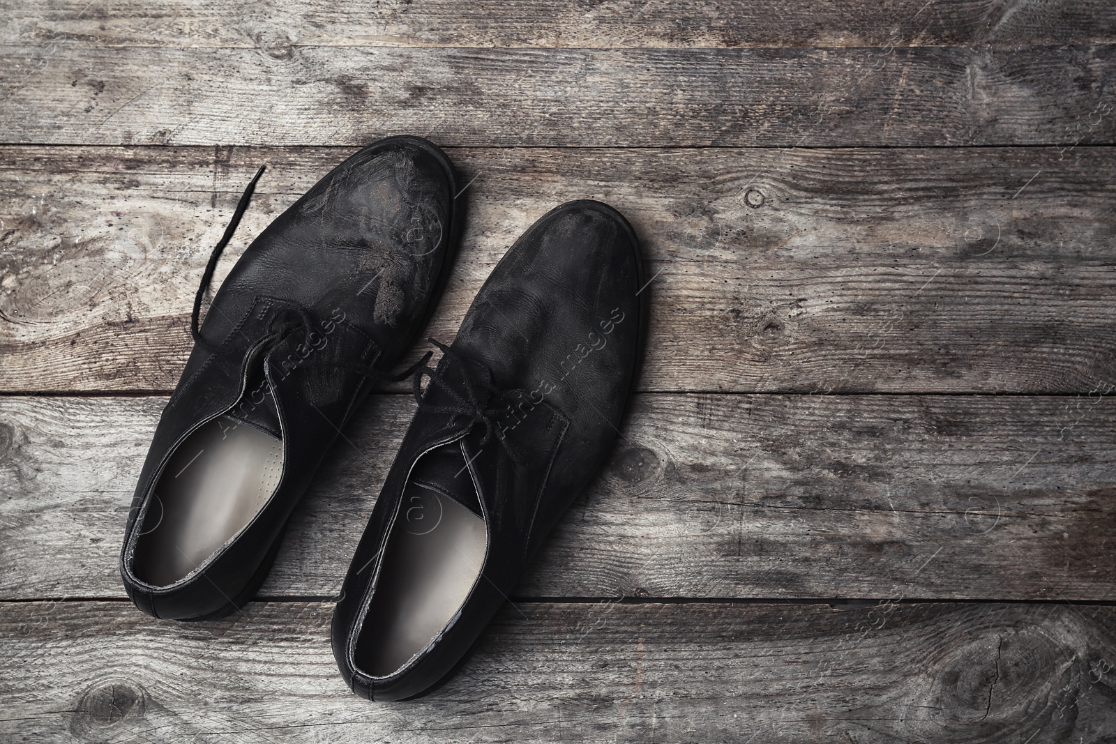 Photo of Dirty shoes and space for text on wooden background, top view. Poverty concept