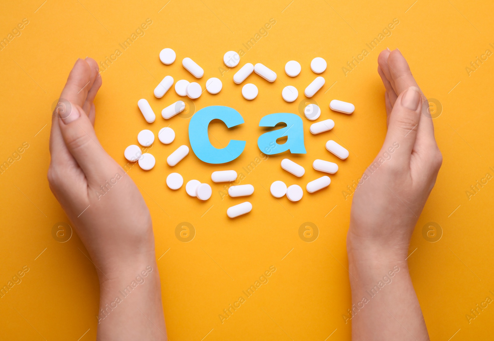 Photo of Woman with pills and calcium symbol made of light blue letters on orange background, top view