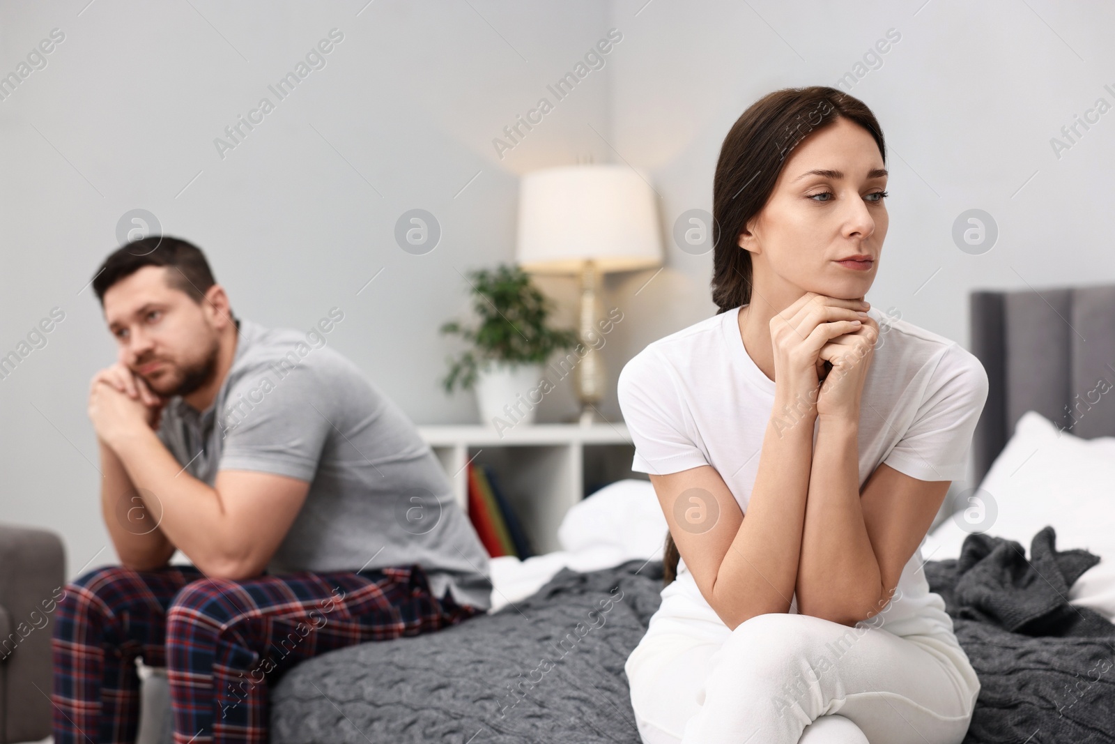 Photo of Offended couple ignoring each other after quarrel in bedroom, selective focus. Relationship problems