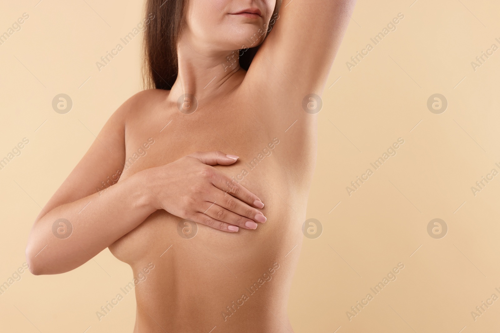 Photo of Naked woman covering her breast on beige background, closeup. Space for text