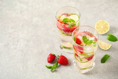 Photo of Tasty refreshing drink  with strawberry on light grey table. Space for text
