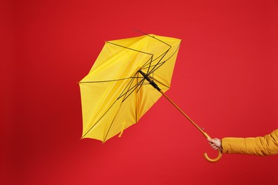 Photo of Woman holding umbrella caught in gust of wind on red background, closeup