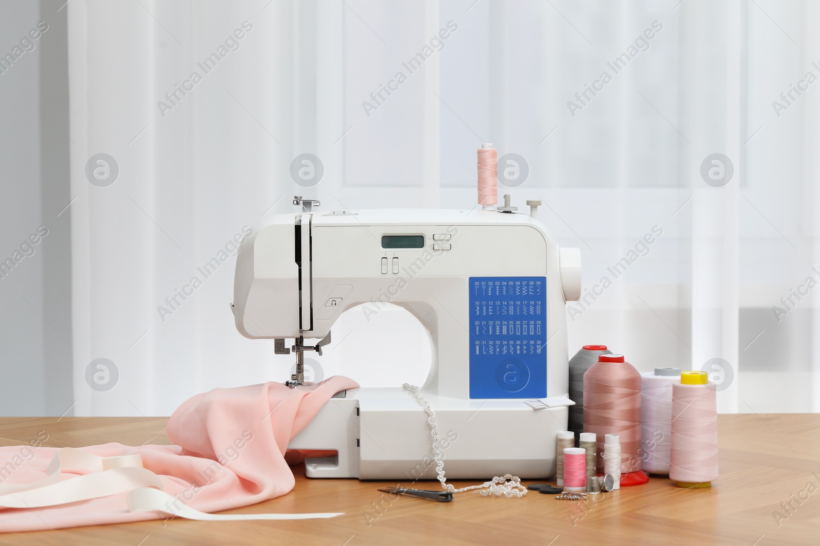 Photo of Sewing machine with fabric and craft accessories on wooden table indoors