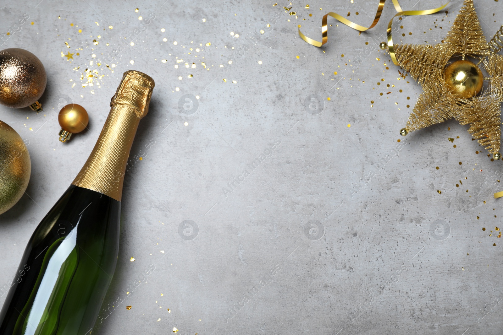 Photo of Happy New Year! Flat lay composition with bottle of sparkling wine on light grey table, space for text