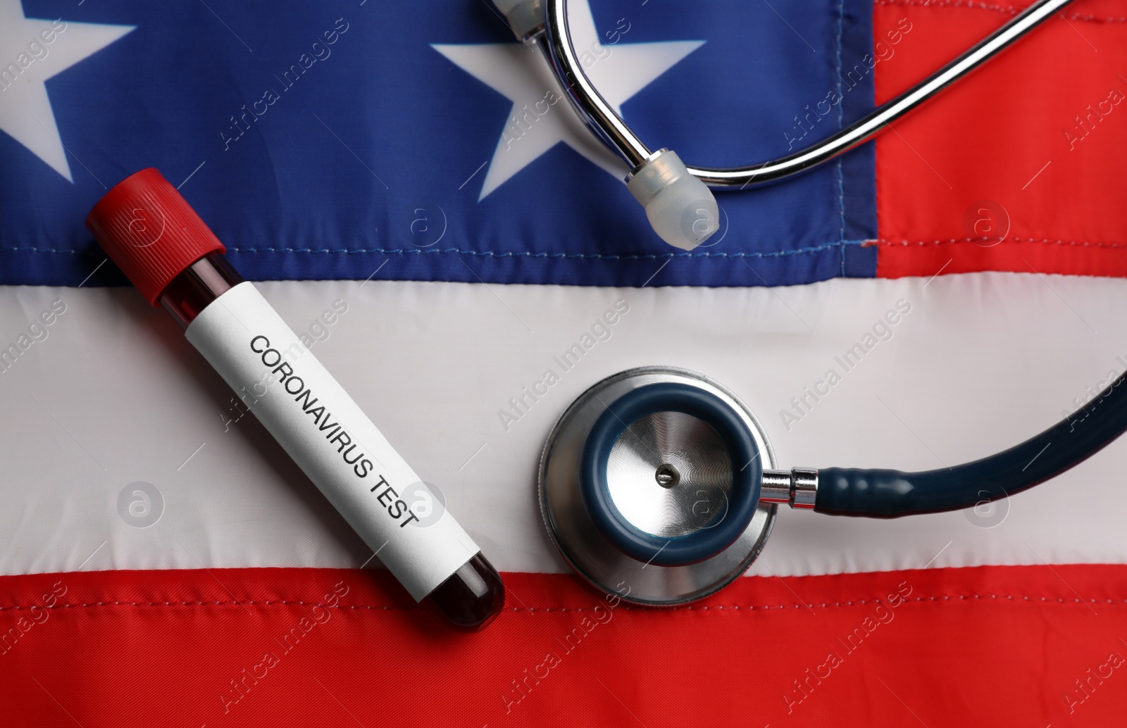 Photo of Test tube with blood sample and stethoscope on American flag, flat lay. Coronavirus pandemic in USA