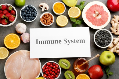 Photo of Card with phrase Immune System and fresh products on grey background, flat lay