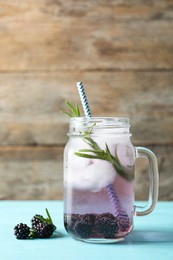 Image of Refreshing blackberry drink with rosemary and ice cubes in mason jar on turquoise wooden table