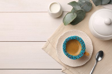 Flat lay composition with delicious edible biscuit cup of espresso decorated with sprinkles on white wooden table. Space for text