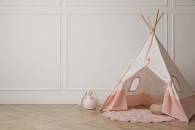 Cute child room interior with play tent near white wall, space for text