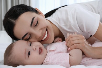 Photo of Young mother with her little baby on bed at home