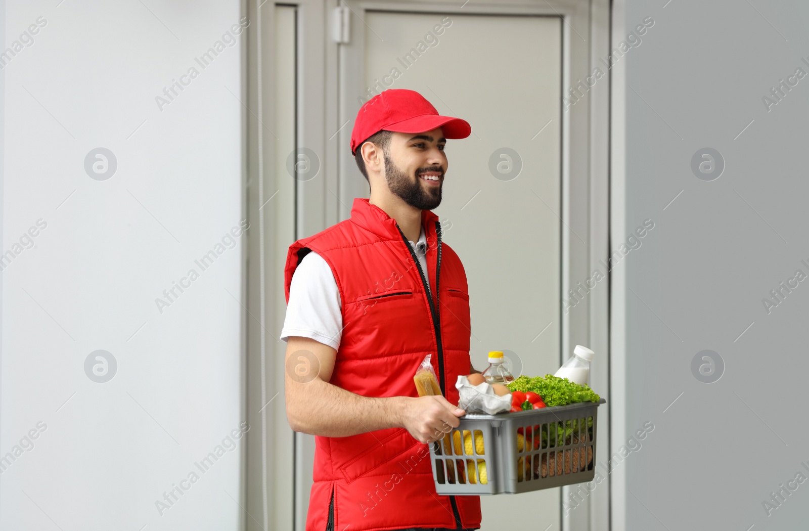 Photo of Man holding basket with fresh products near entrance. Food delivery service