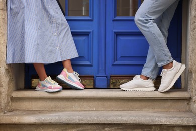 Photo of Woman and man wearing stylish sneakers on stairs outdoors closeup