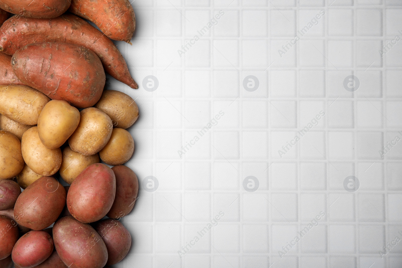 Photo of Different types of fresh potatoes on white table, flat lay. Space for text