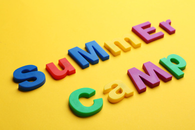 Photo of Phrase SUMMER CAMP made with magnet letters on yellow background, closeup