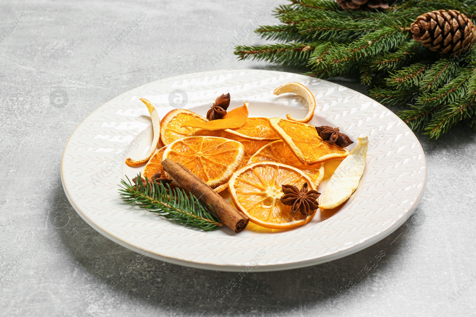 Photo of Composition with dry orange slices, anise stars and fir branches on light grey table