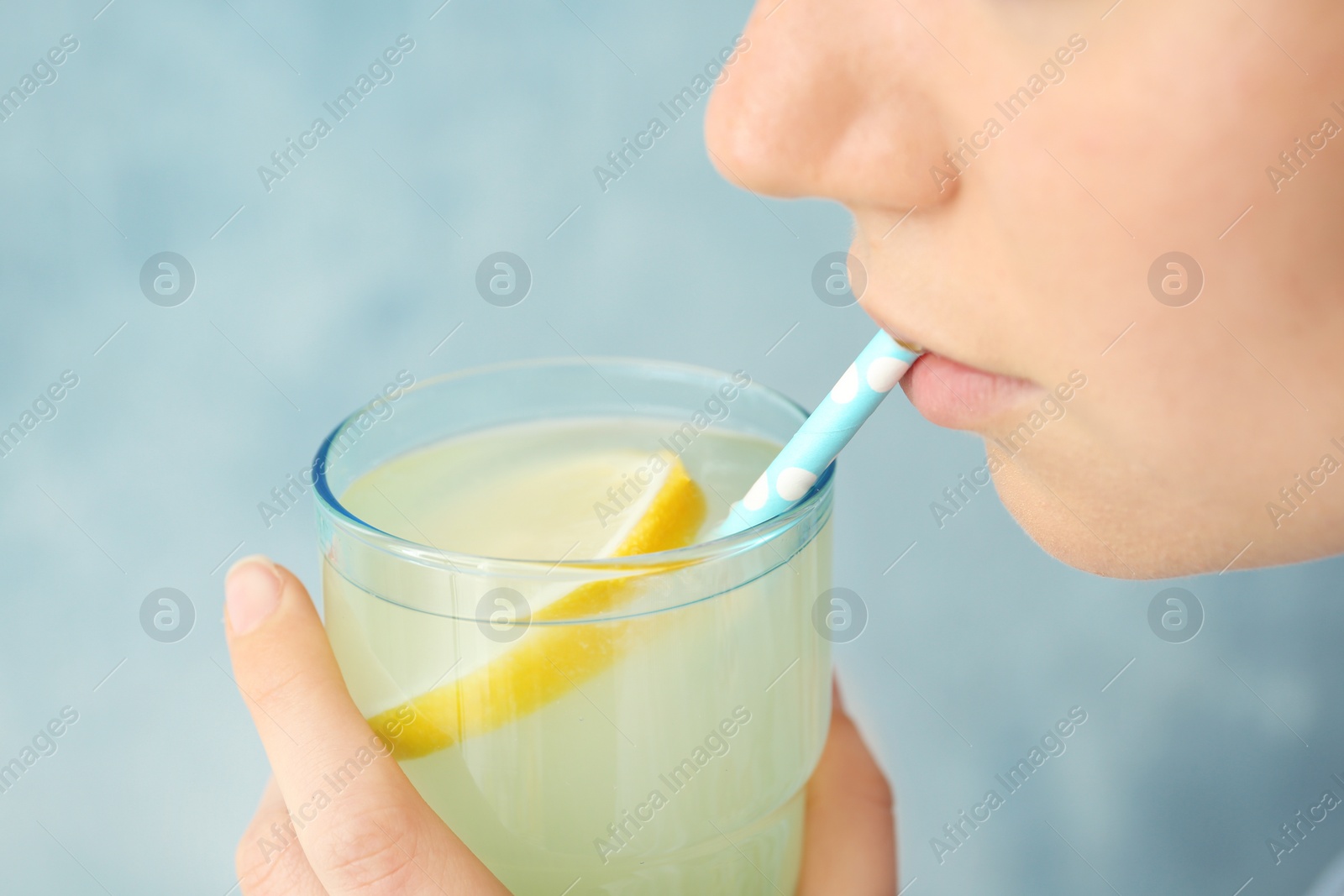 Photo of Young woman drinking lemon cocktail against color background