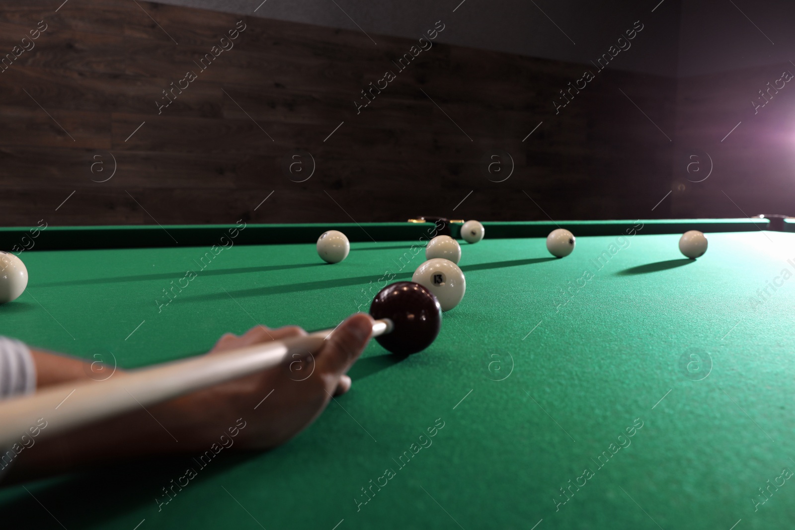 Photo of Young man playing Russian billiard indoors, closeup