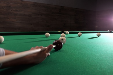 Photo of Young man playing Russian billiard indoors, closeup