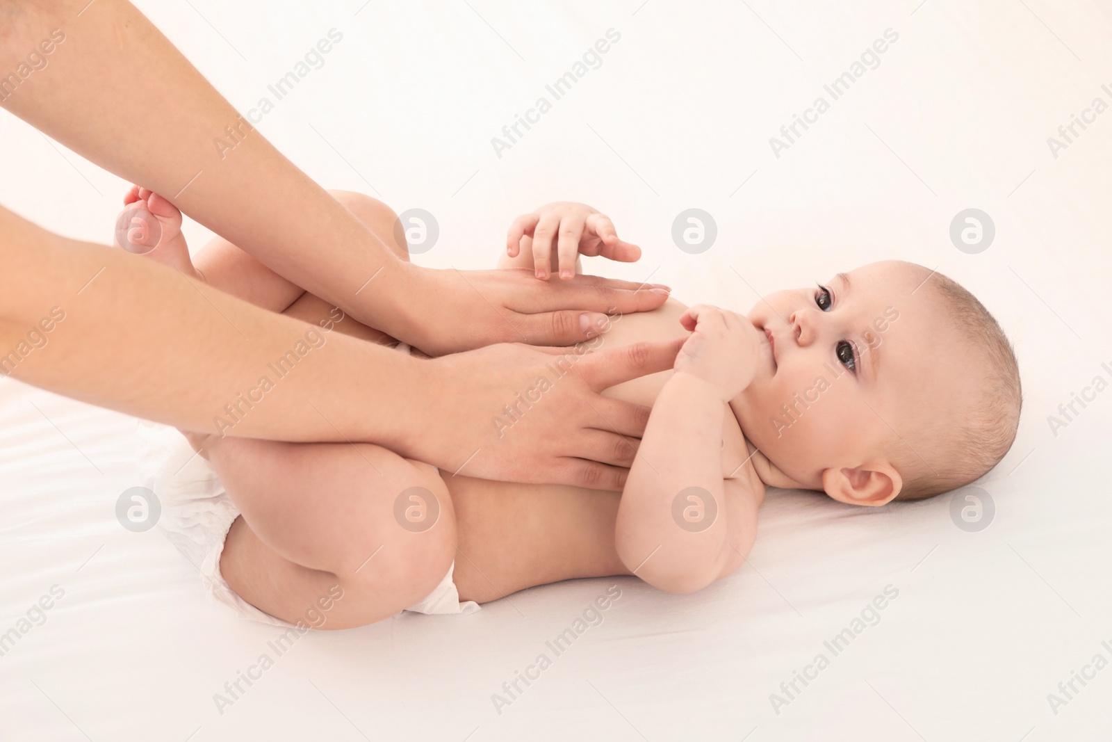 Photo of Mother and her cute child on white bed. Baby massage and exercises