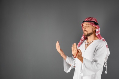Photo of Muslim man praying on gray background. Space for text