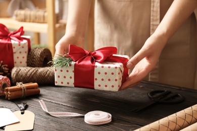 Woman holding Christmas gift over wooden table