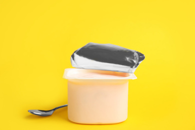 Tasty organic yogurt in plastic cup on yellow background