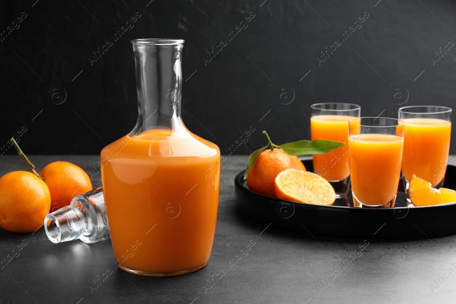 Photo of Delicious tangerine liqueur and fresh fruits on grey table