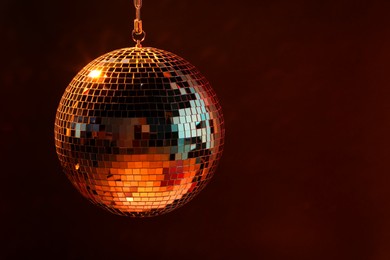 Photo of Shiny bright disco ball on dark background, space for text