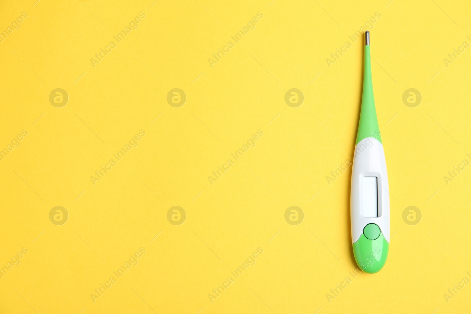 Photo of Modern digital thermometer on yellow background, top view. Space for text