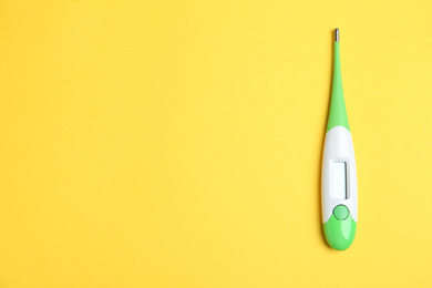 Photo of Modern digital thermometer on yellow background, top view. Space for text