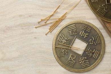 Photo of Acupuncture needles and ancient coin on beige marble table, flat lay. Space for text