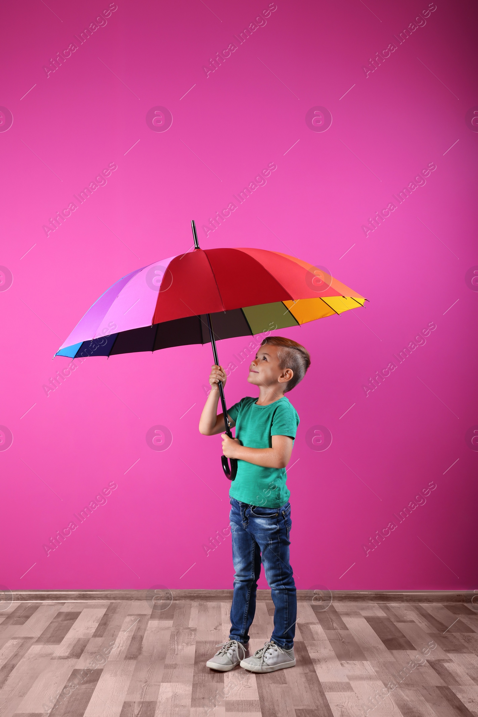 Photo of Little boy with rainbow umbrella near color wall