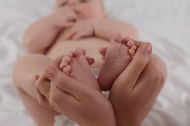 Photo of Mother holding feet of her newborn baby on bed, closeup