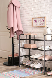 Shelving rack with stylish women's shoes and accessories near white brick wall indoors
