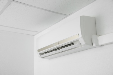 Photo of Modern air conditioner on white wall indoors