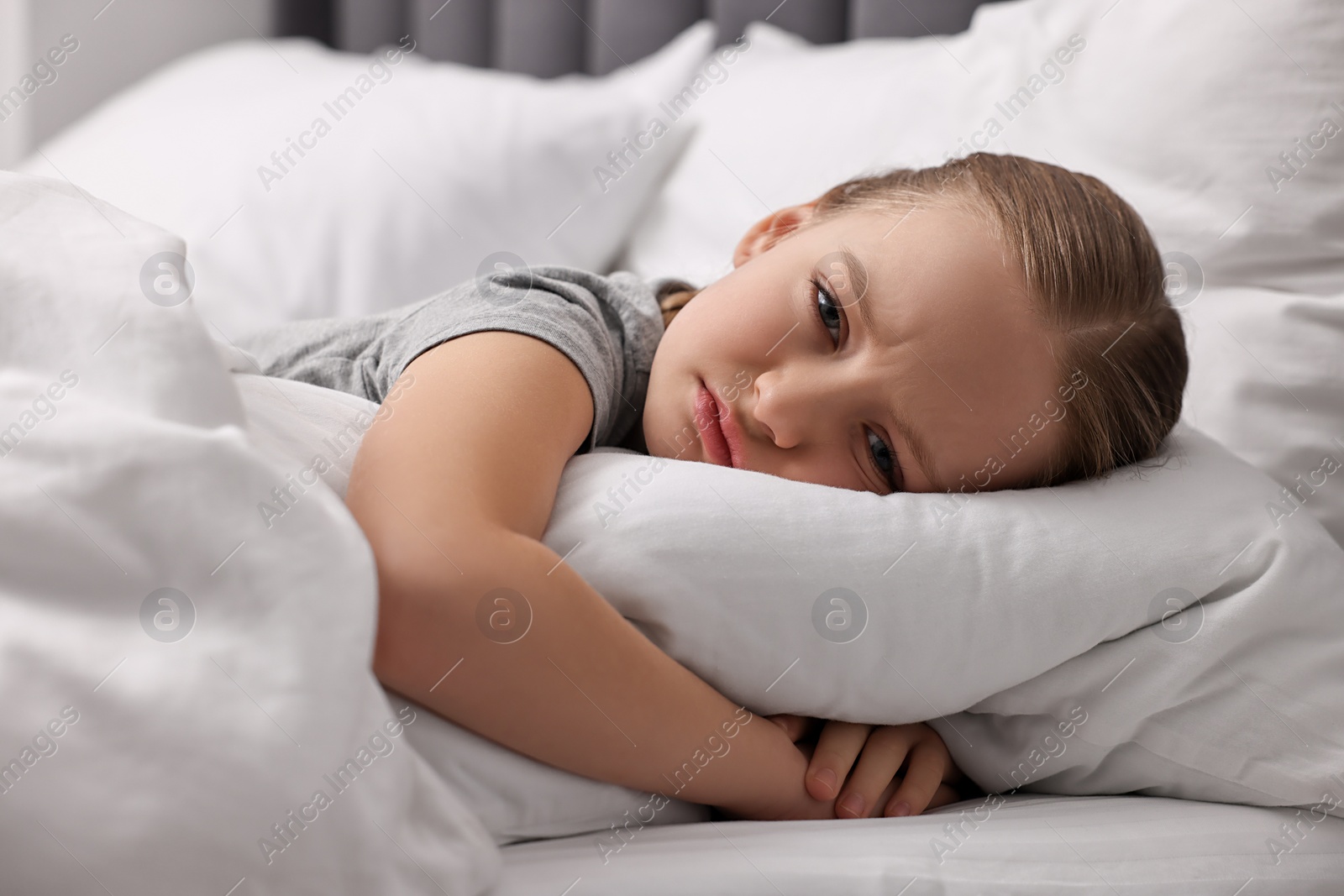 Photo of Little girl suffering from headache in bed