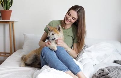Young woman and Akita Inu dog in bedroom decorated with houseplants