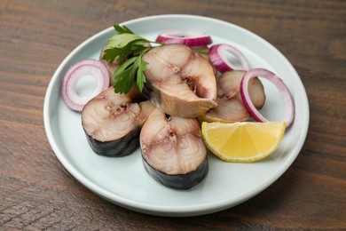 Photo of Slices of tasty salted mackerel with lemon wedge, onion rings and parsley on wooden table, closeup