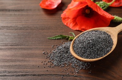 Photo of Spoon of poppy seeds and flower on wooden table, space for text