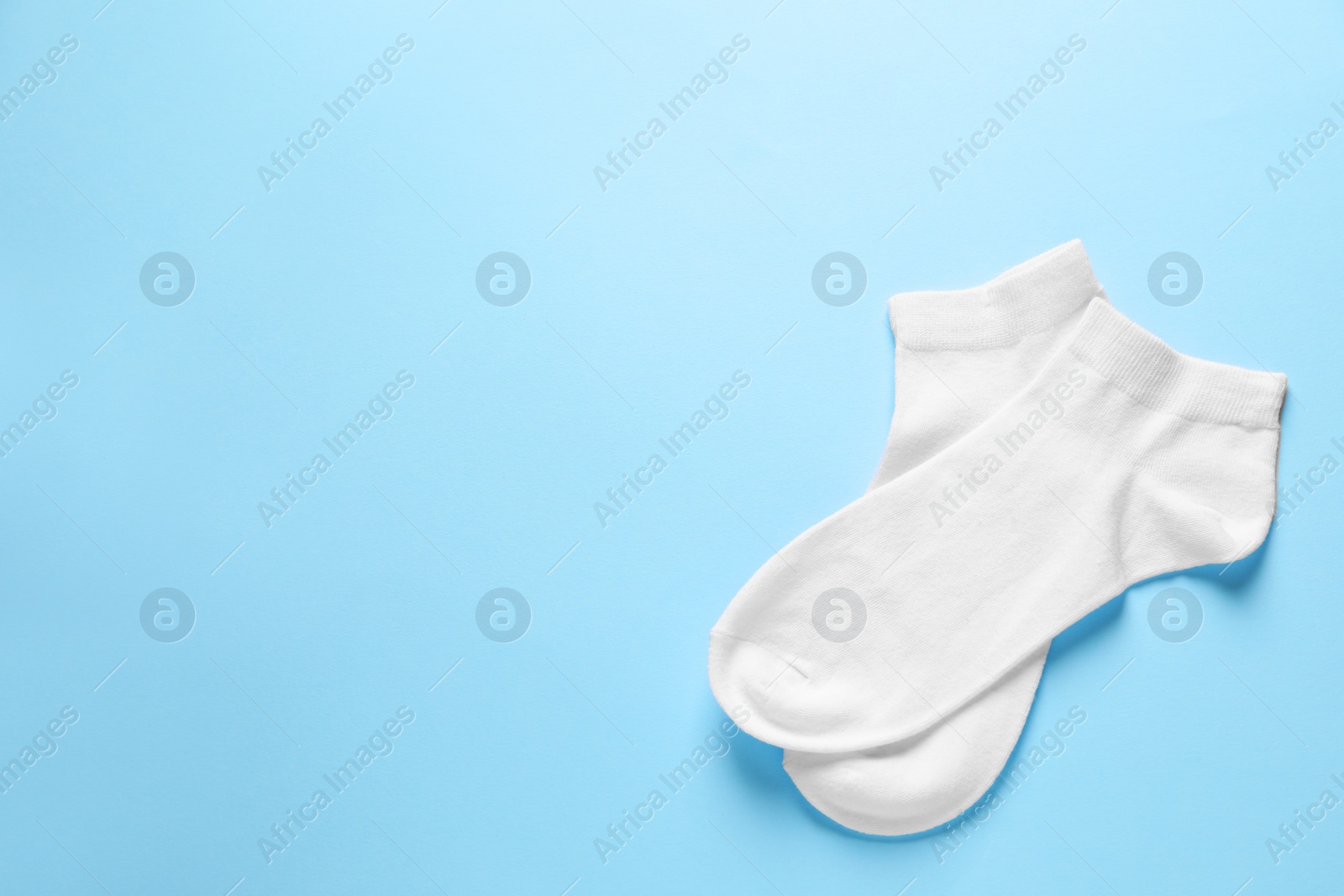 Photo of Pair of white socks on light blue background, flat lay. Space for text