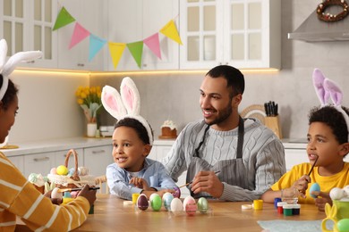 Photo of Happy African American family painting Easter eggs at table in kitchen